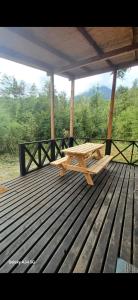 a wooden table on a deck with a view of the forest at Entre Bosque Puelo in Puelo