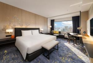 a hotel room with a large bed and a desk at Hotel Nikko Kaohsiung in Kaohsiung