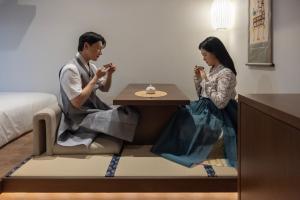 a man and woman sitting at a table in a room at Onjae Stay Seongsu in Seoul