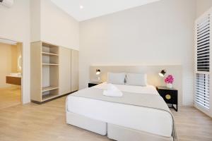 a white bedroom with a large bed and a bathroom at Picnic Bay Hotel in Picnic Bay +39 photos