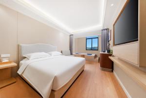 a bedroom with a white bed and a flat screen tv at Tangshan Yipin Hot Spring Hotel in Nanjing