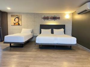 a bedroom with two beds and a brick wall at BB Glass House Pattanakrn บีบี กลาสเฮ้าส์ พัฒนาการ in Bangkok
