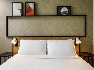 a bed with two white pillows and two tables at Hotel ibis Guimaraes in Guimarães +129 photos