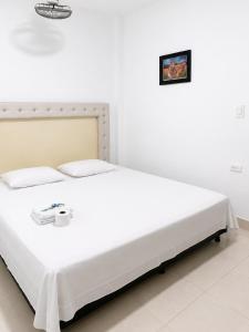 a white bed in a white room with at Casa Hotel Ortiz in Apartadó