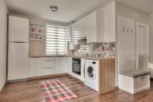 a kitchen with white cabinets and a washer and dryer at Tuzlaks appartment in Sarajevo