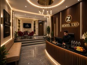 a man sitting at a reception desk in a hotel lobby at ZED Plaza in New Delhi