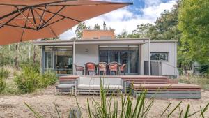 a small house with chairs and an umbrella at Aria House in Trentham