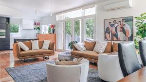 a living room with couches and chairs and a kitchen at Aria House in Trentham