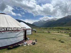 a tent in a field with mountains in the background at Yurt On The Mountain -With us you will feel the spirit of nomads in Svetlaya Polyana
