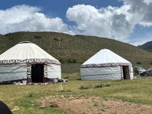 two white tents in a field with a hill in the background at Yurt On The Mountain -With us you will feel the spirit of nomads in Svetlaya Polyana +24 photos