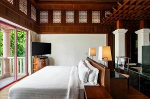 a bedroom with a white bed and a tv at Centara Grand Beach Resort Phuket in Karon Beach