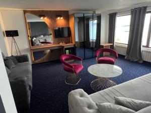 a hotel room with a couch and chairs and a television at Saint George - Old Nesebar in Nesebar