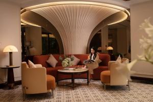 a woman sitting on a couch in a hotel lobby at Luxeden Signature hotel in Hanoi