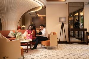 a man and a woman sitting on a couch in a lobby at Luxeden Signature hotel in Hanoi
