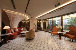 a lobby with orange chairs and tables and windows at Luxeden Signature hotel in Hanoi