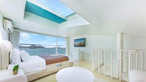a bedroom with a bed and a large window at Geoje Marepos Pension in Geoje