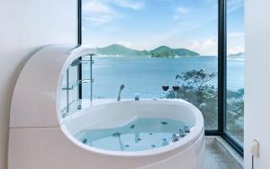 a bath tub with a view of the ocean at Geoje Marepos Pension in Geoje
