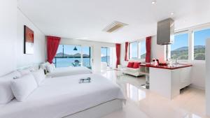 a white bedroom with a large bed and a desk at Geoje Marepos Pension in Geoje