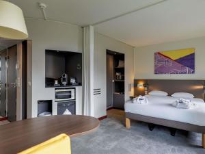 a hotel room with a bed and a table at Novotel Suites Paris Stade de France in Saint-Denis