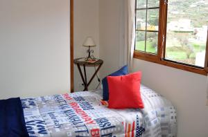 1 dormitorio con cama con almohada roja y ventana en Casa Paco Las Vegas, en Valsequillo