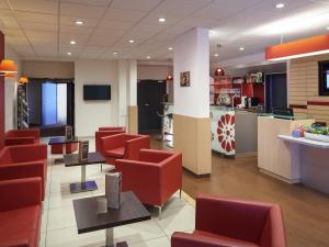 a waiting room with red chairs and a counter at ibis Cholet in Cholet