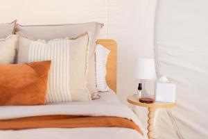 a bed with white and orange pillows and a side table at Captain Thunderbolt Bubbletent at Mirumiru in Tenterfield