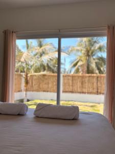 a bed with two pillows in front of a window at Bamboo in El Paredón Buena Vista