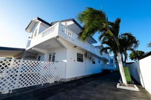 a white house with a palm tree in front of it at Rowy's appartement in Willemstad