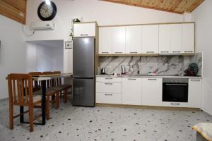 a kitchen with white cabinets and a stainless steel refrigerator at Lakeview Villa Nardi in Ksamil