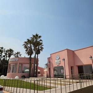 a pink building with palm trees in front of it at South Sagye Jeju in T'ogi-dong