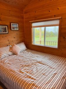 a large bed in a wooden room with a window at Bras D'Or Lakes Campground in Baddeck Inlet