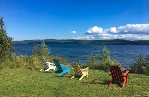 a group of chairs sitting next to a lake at Bras D'Or Lakes Campground in Baddeck Inlet