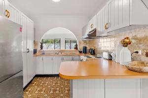 a kitchen with white cabinets and a wooden counter top at Coastline Callala - Fire Pit - Pet Friendly in Callala Beach