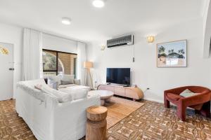 a living room with a white couch and a tv at Coastline Callala - Fire Pit - Pet Friendly in Callala Beach