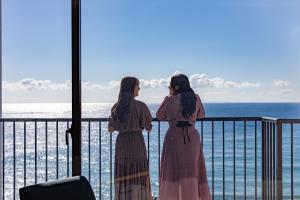 two women standing on a balcony looking at the ocean at Atagawa Ocean Resort in Higashiizu