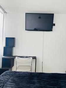 a bedroom with a bed and a chair and a tv at Lagom 406 Habitación en depa duplex in Mexico City +3 photos