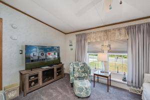 a living room with a television and a chair at One Peace Cottage in Deep Hole