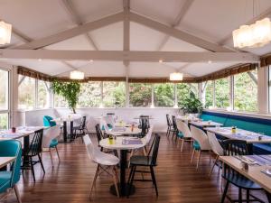 a dining room with tables and chairs and windows at ibis Styles Quimper in Quimper
