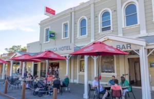 a group of people sitting at tables in front of a bar at ARK Apartments in Echuca