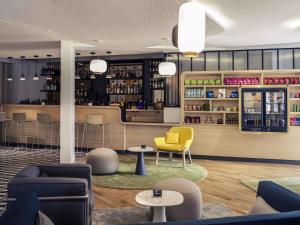 a lobby with a bar with a yellow chair and tables at Mercure Nantes Centre Gare in Nantes