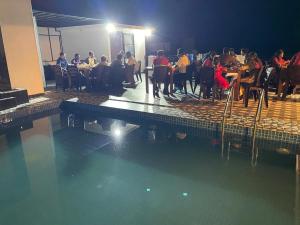 a group of people sitting at tables in a swimming pool at JK Residence Trincomalee in Trincomalee