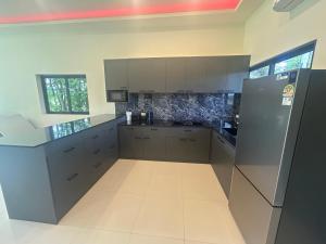 a large kitchen with white cabinets and a refrigerator at Private Pool Villa Huay Yai in Ban Bung