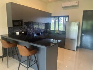 a kitchen with a black counter and a refrigerator at Private Pool Villa Huay Yai in Ban Bung