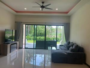 a living room with a couch and a ceiling fan at Private Pool Villa Huay Yai in Ban Bung