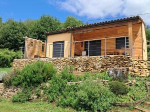 a log house with a stone wall in front of it at Gîte des petites pyrénées in Ausseing