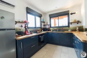 a kitchen with navy blue cabinets and windows at Gîte des petites pyrénées in Ausseing +10 photos