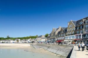 a group of people walking along a beach with buildings at Entre terre et mer in Cherrueix