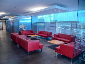 a waiting room with red leather chairs and tables at ibis Montevideo Rambla in Montevideo