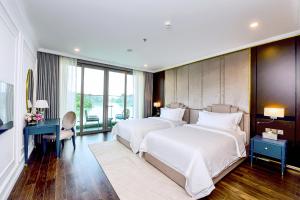 a bedroom with two beds and a desk and a television at Centara Hotel & Residences Van Don in Cái Rồng
