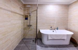 a bathroom with a bath tub and a sink at Centara Hotel & Residences Van Don in Cái Rồng